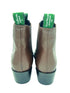 Pair of brown leather boots with green labels on a white background