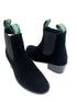 Black ankle boots with green tags on a white background